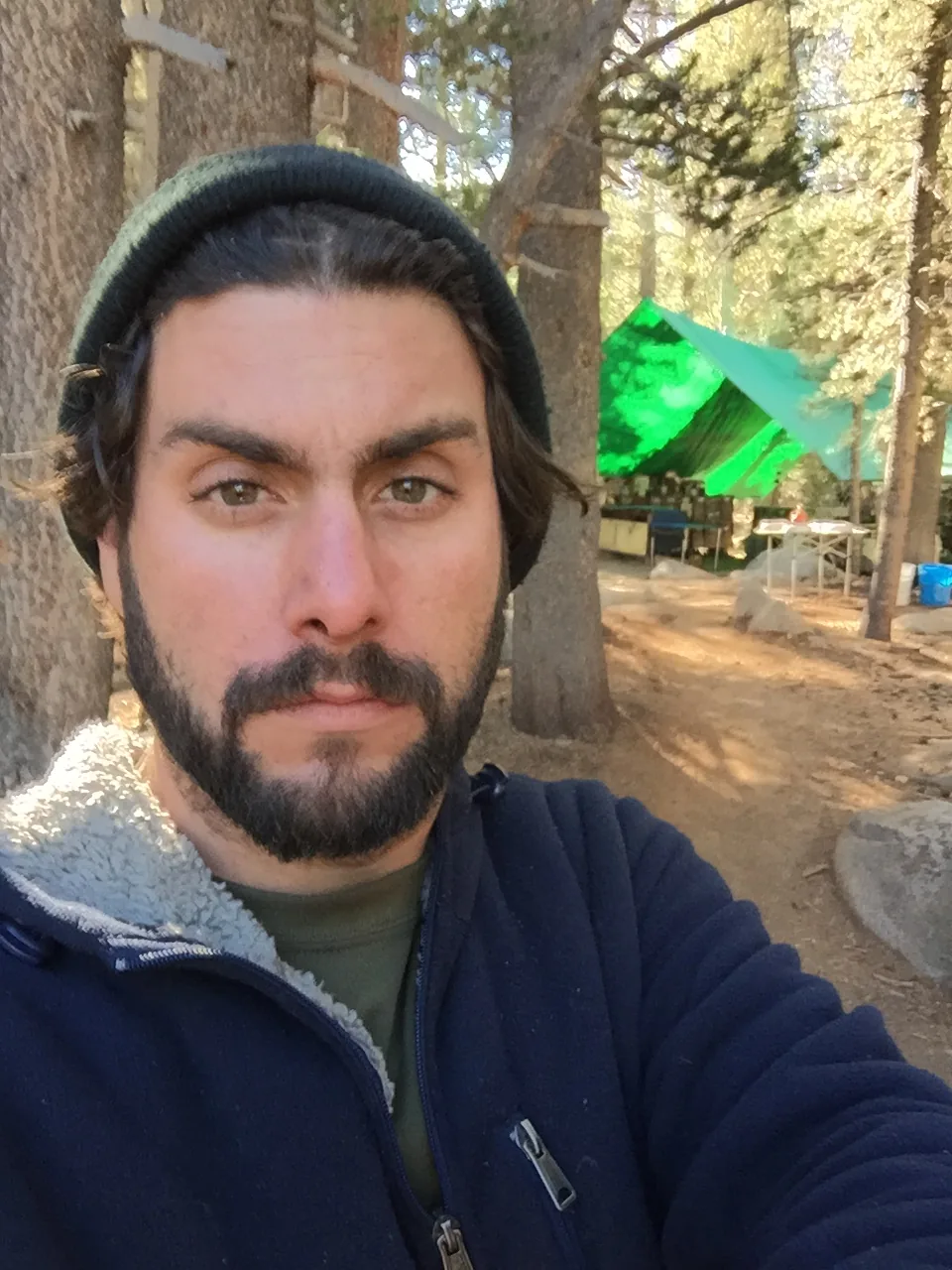 Jason Blazer outdoors with the green-tarp camp kitchen behind him