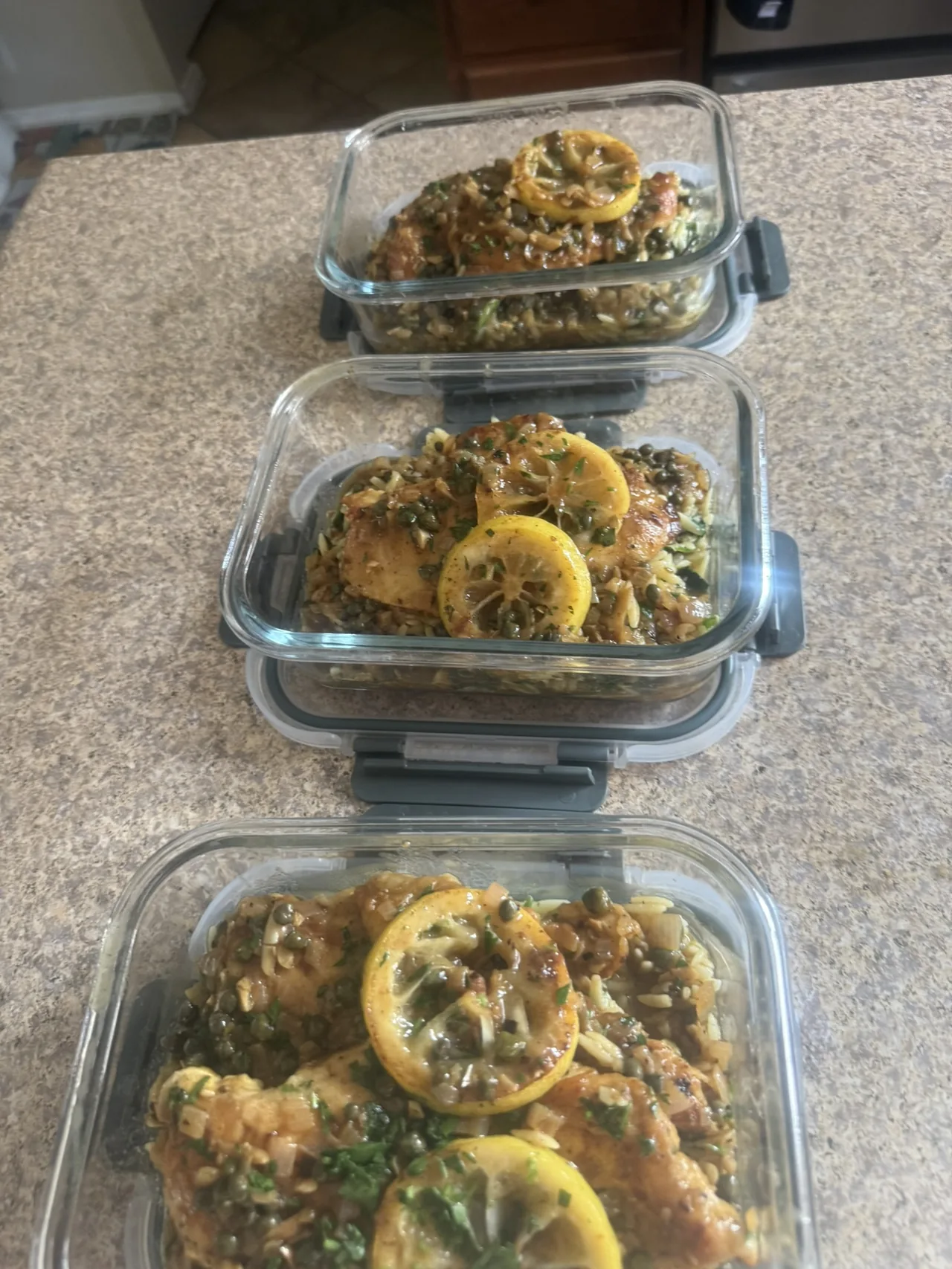 Glass containers holding lemon-and-caper chef-prepared meals